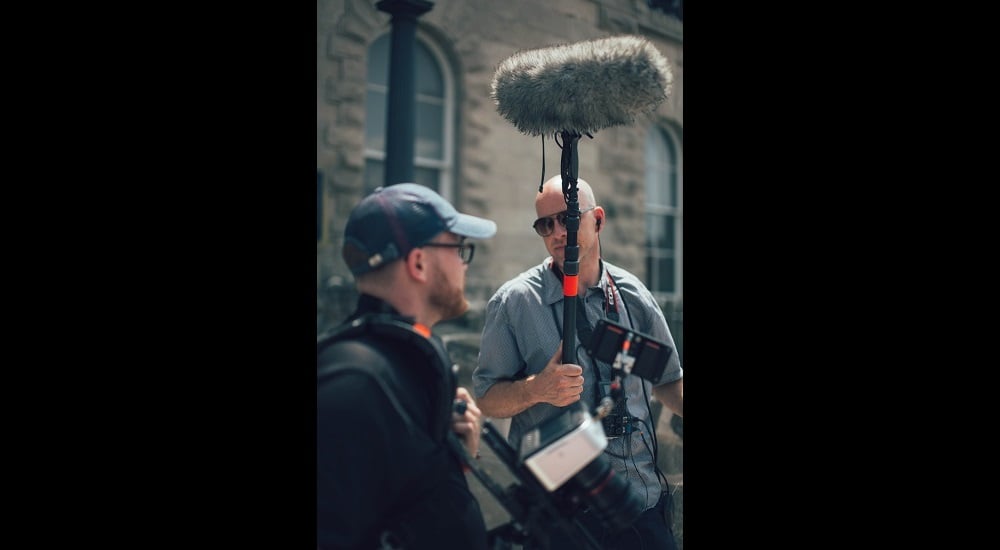 Sound guy holding boom mic on film set | Scratch Tracks and why they matter in film production